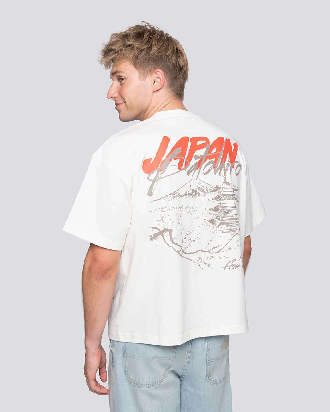 Mladý muž s bavlněným tričkem s nápisem "JAPAN" a stylovým designem.