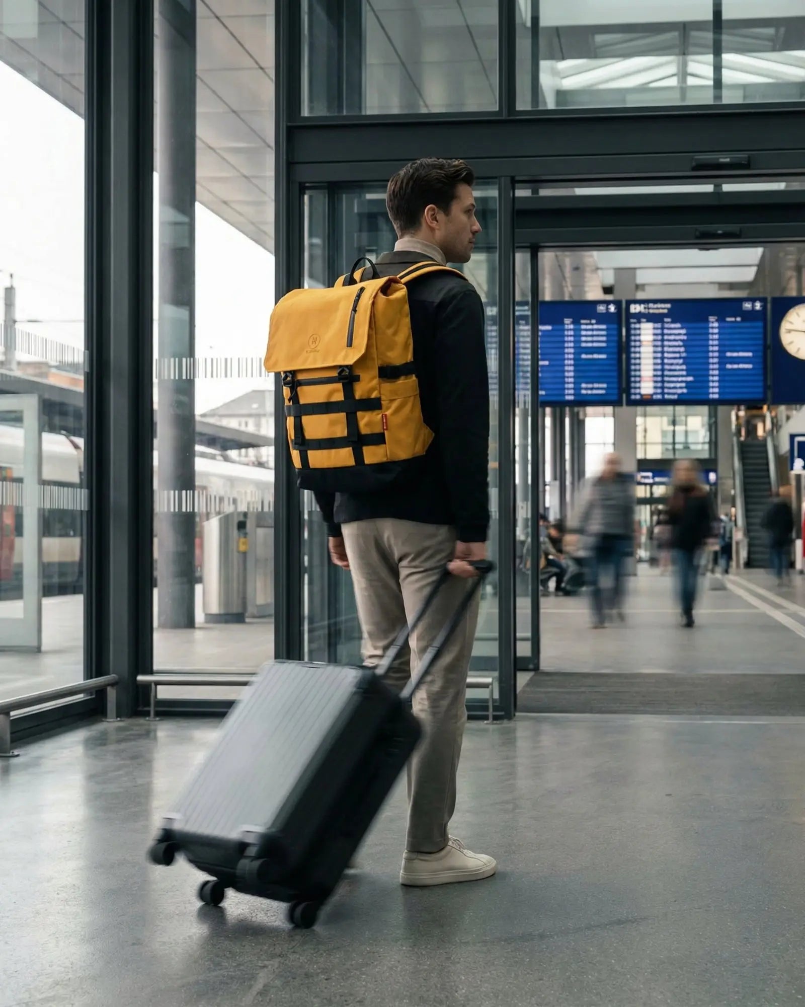 Man with Minato Premium 6.0 – Yellow Black backpack walking through a train station.