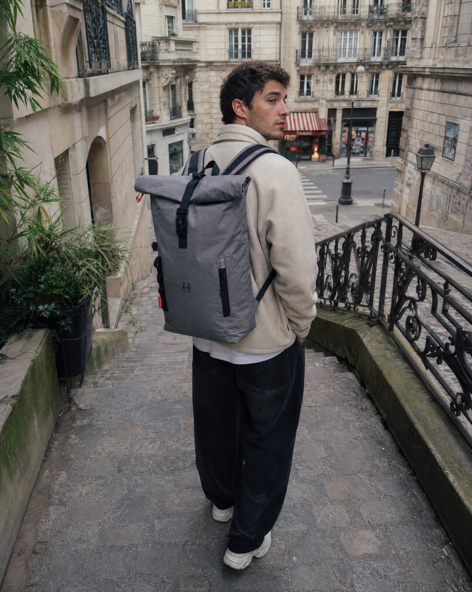 Roku Everyday 20L Steel Gray rolovací batoh 20l auf einer Treppe in der Stadt getragen von einem Modell.