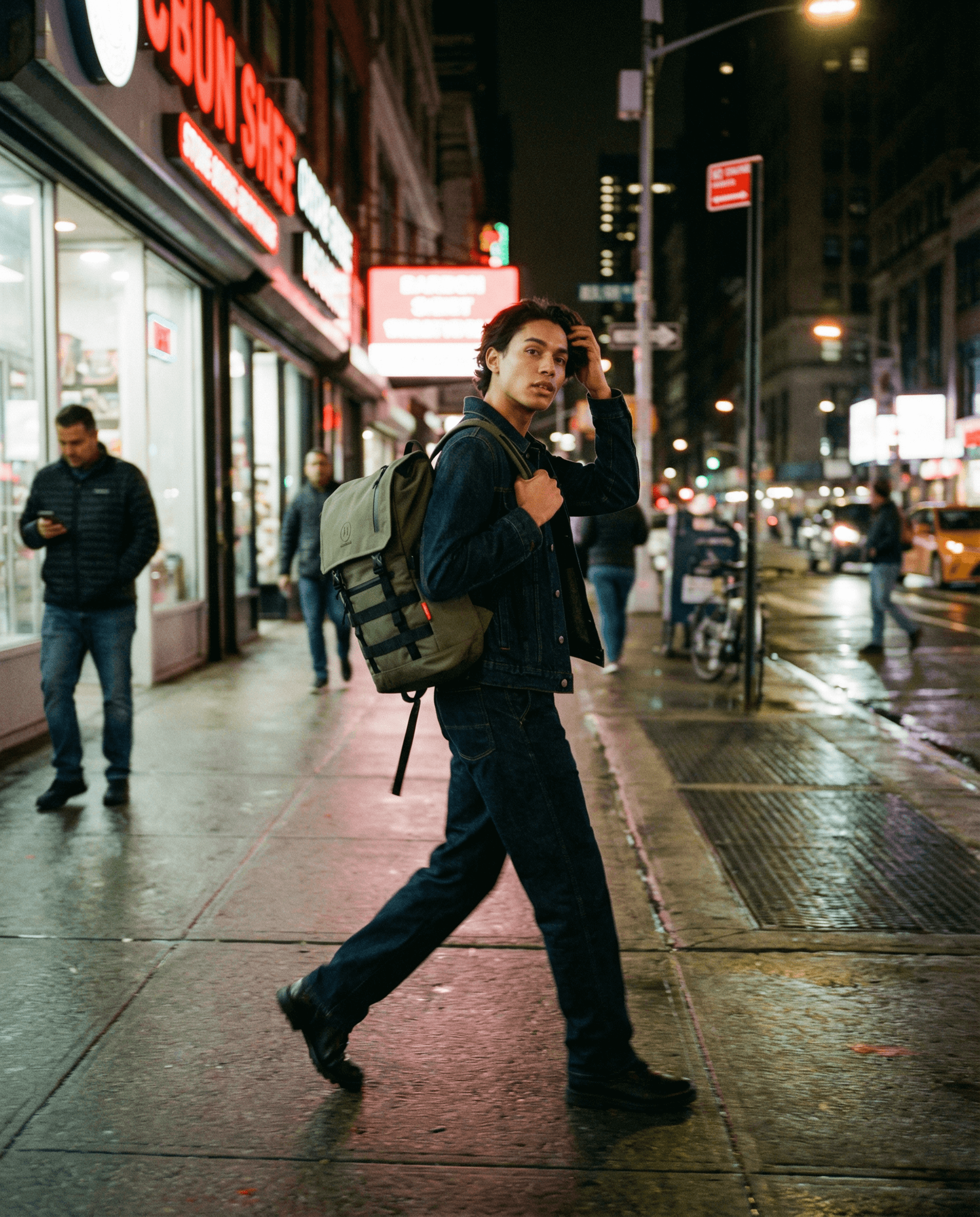 Minato Premium 6.0 – Ranger Green backpack worn by a man walking in a city at night.