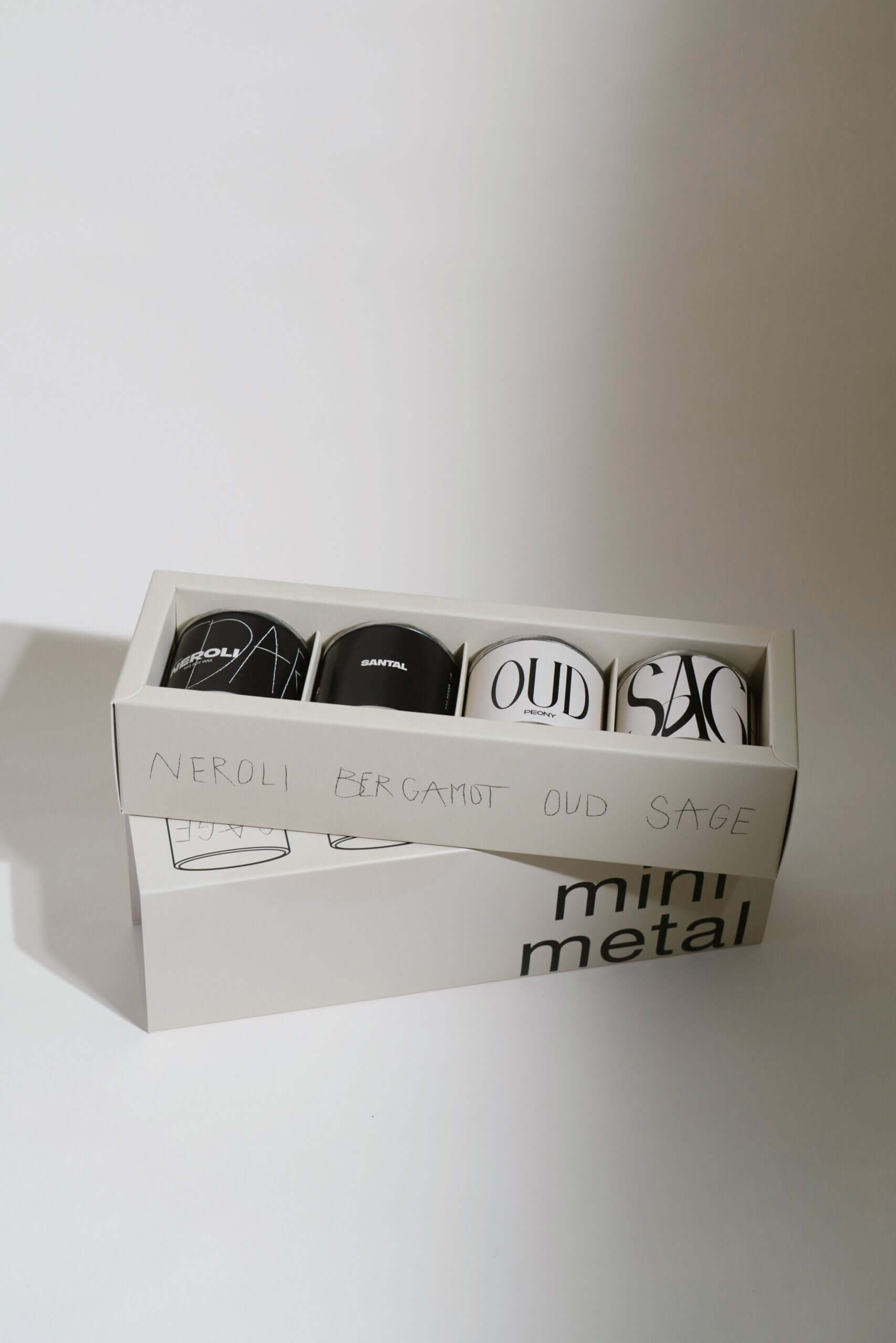 Mini Metal Tins Set featuring elegant scented candles: Neroli, Bergamot, Oud, and Sage in stylish packaging.