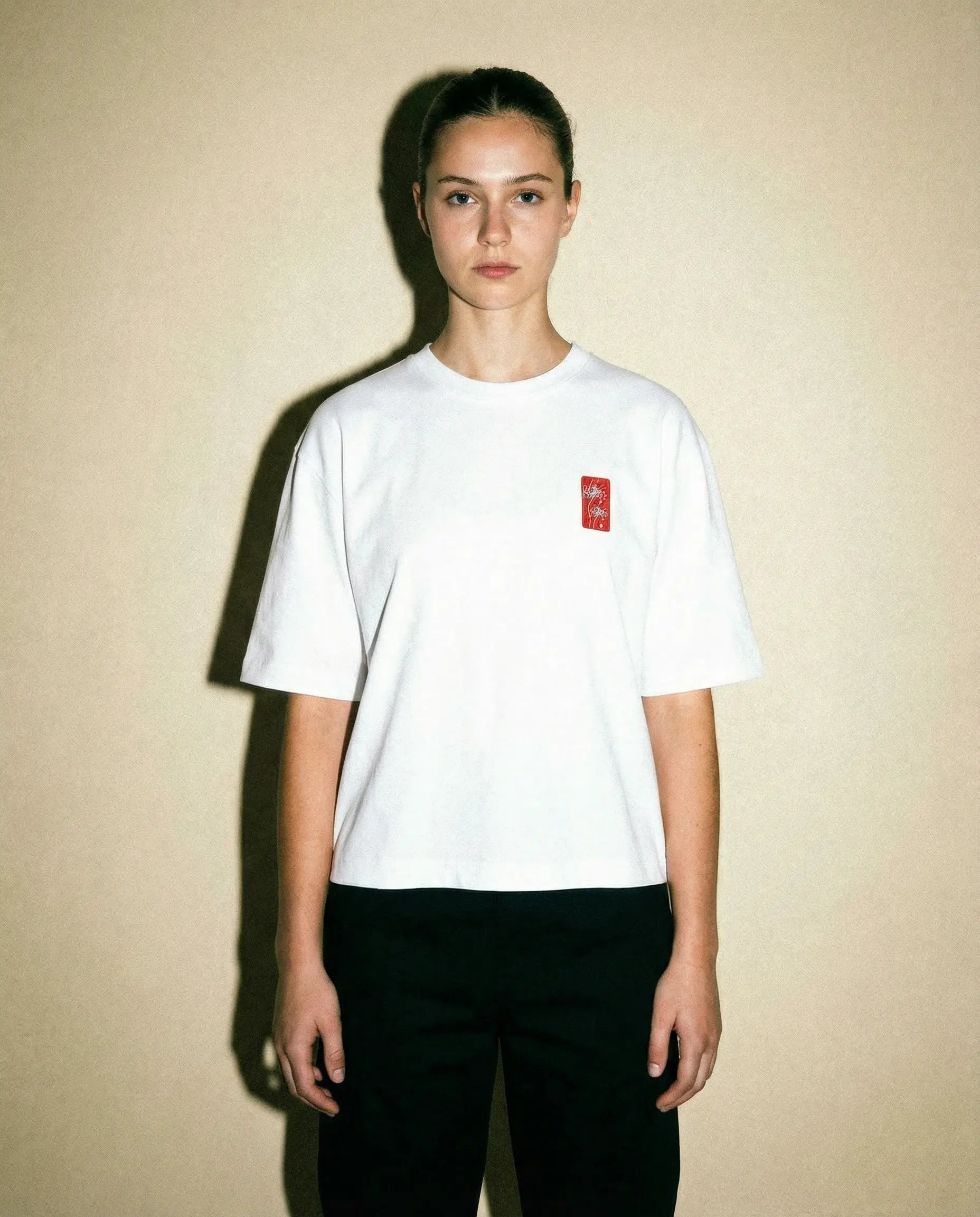Spider Lily – Weißes, kurz geschnittenes Oversize-T-Shirt an einem Model vor neutralem Hintergrund.