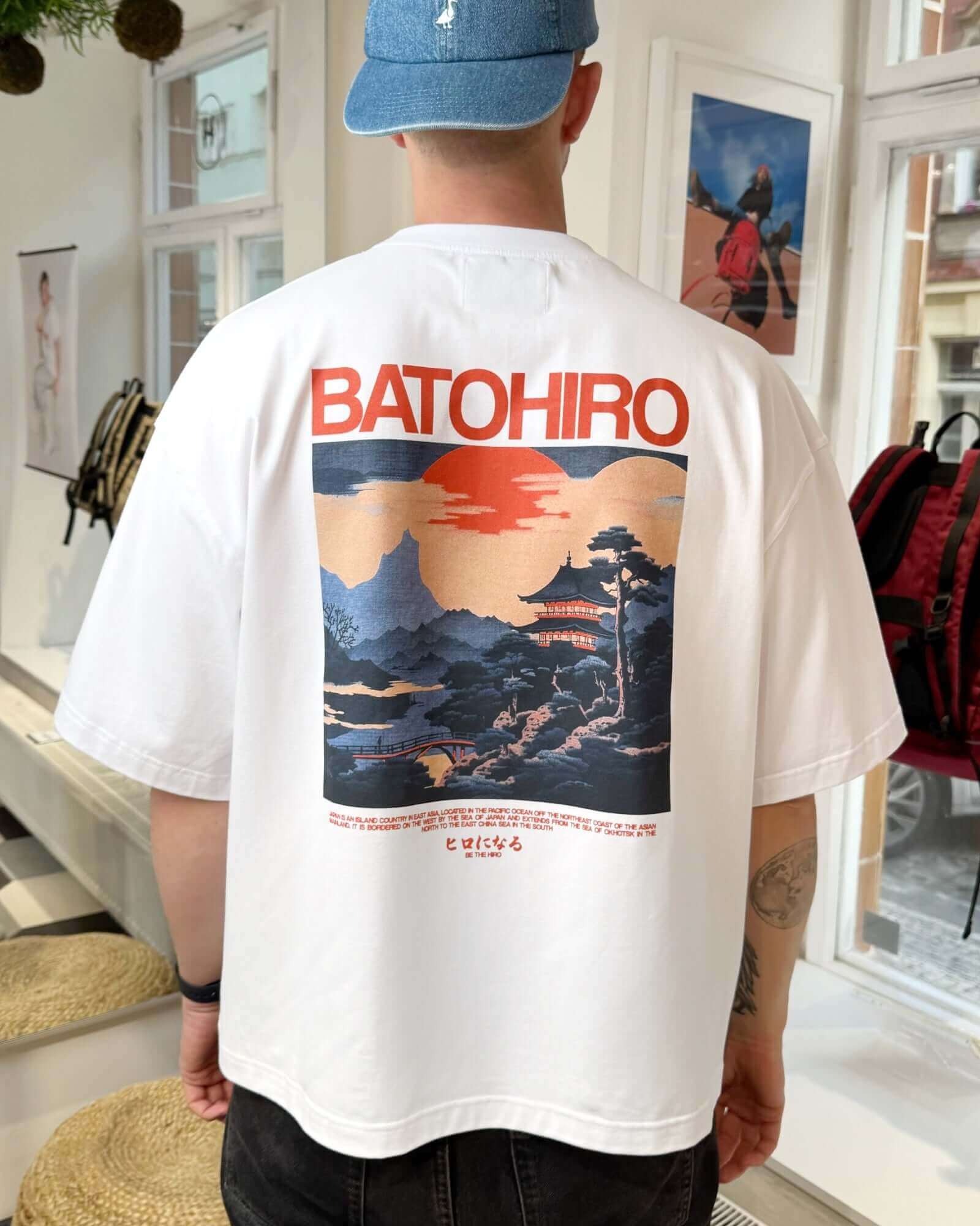Back view of a man in a white cropped oversized tee featuring Batohiro's unique graphic design.