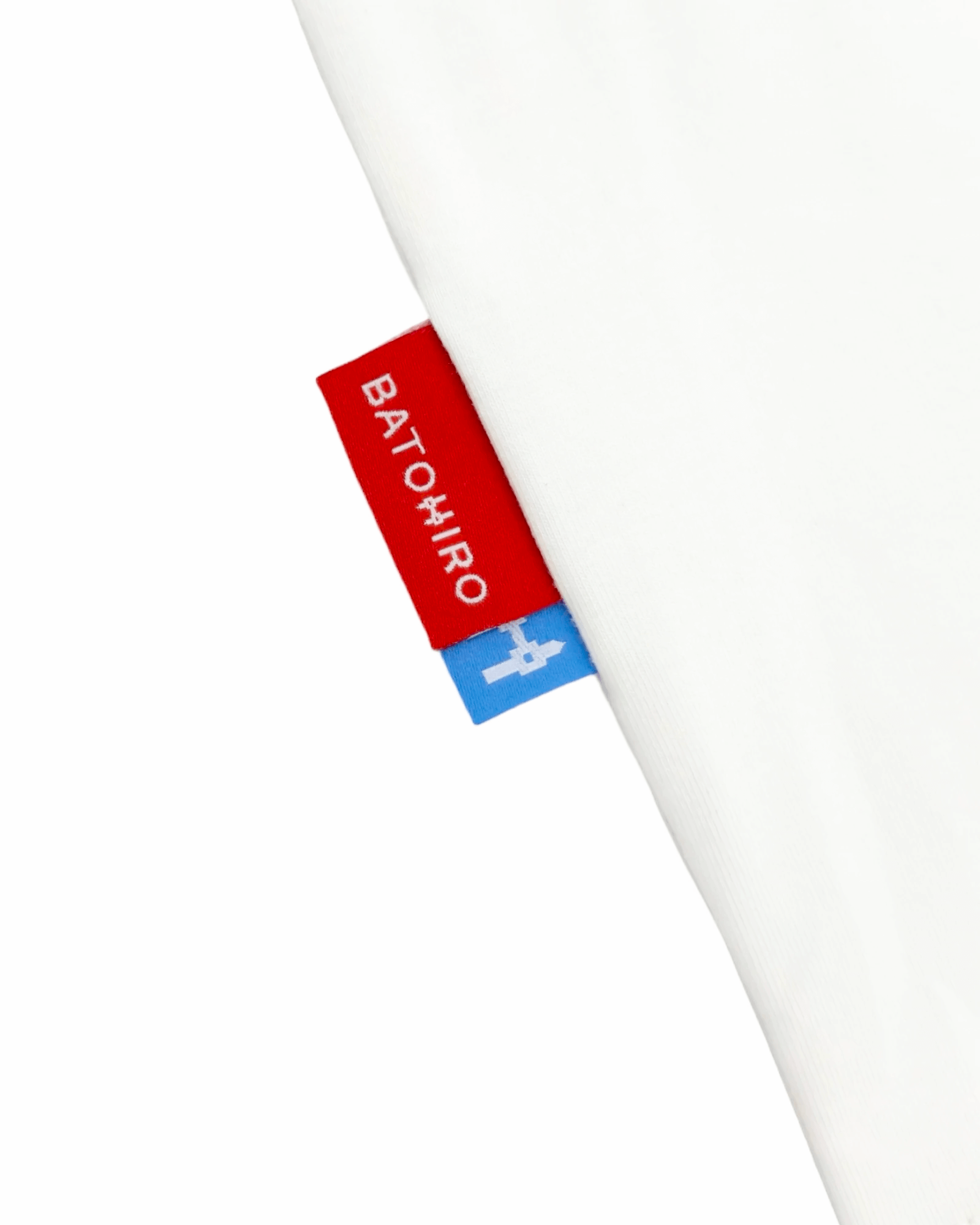 Close-up of cream white Batohiro tee with red and blue tags, showcasing quality Czech craftsmanship and design.